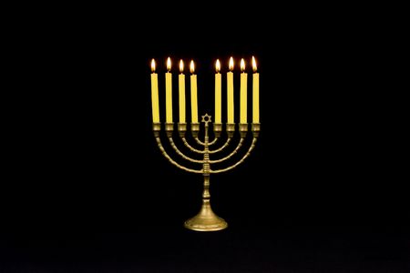Horizontal image of a Menorah with burning yellow candles against a black backgroundの写真素材