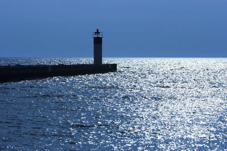 Backlight beacon light at the end on a pier photographed with a blue castの写真素材