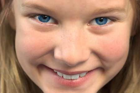 Close up of young girl with blond hair giving a really big smile. Narrow depth of focus.の写真素材
