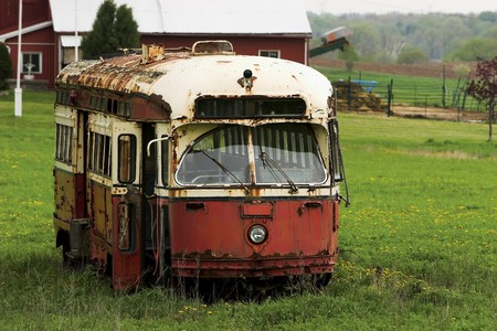 Old red and yellow, rusted and abandoned trolley car in a farmer's field.の写真素材