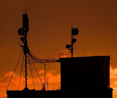 Broadcasting equipment on roof againist sunriseの写真素材