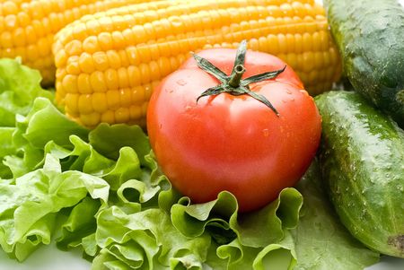 Vegetables close-up: tomatoes, cucumbers, corn on the leaves of lettuce.の写真素材