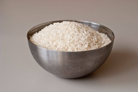 Bowl of dry rice on a gray background. Variety of rice with round grain.の写真素材