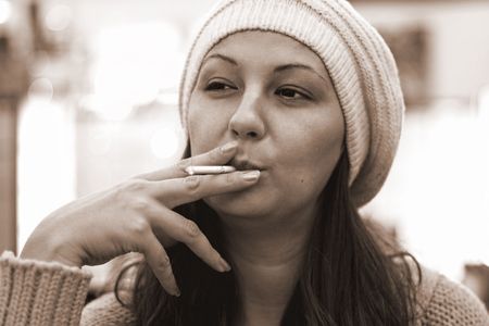 A girl pulls in cigarette smoke dreamily.の写真素材