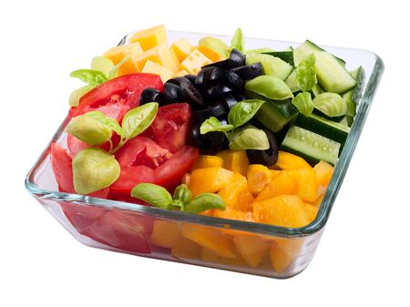 Sliced vegetables (tomatoes, peppers, olives and basil) and cheese in a transparent plateの写真素材