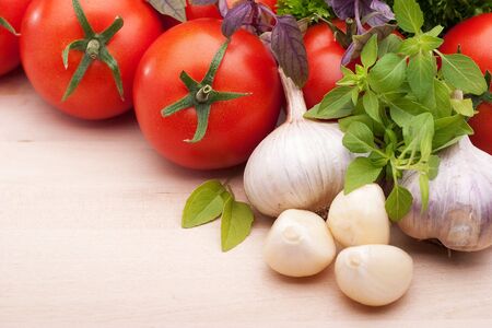 Still life: tomatoes, garlic and basil on a light backgroundの写真素材