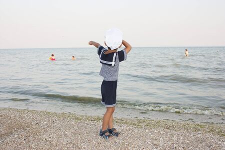 Beautiful 4 year old boy smiling and posing in captains hat against the background of the sea.の写真素材