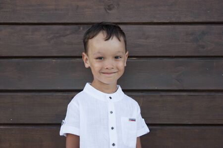 Handsome 4 year old boy smiling on a blackboard backgroundの写真素材