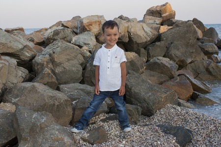 Boy child on sea stones smiles beautifullyの写真素材