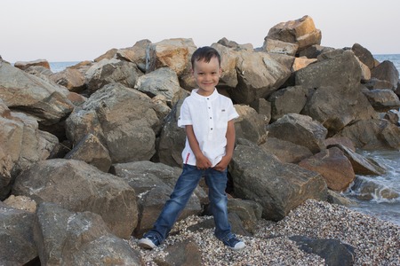 Boy child on sea stones smiles beautifullyの写真素材