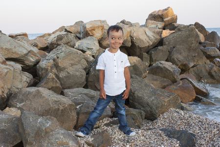 Boy child on sea stones smiles beautifullyの写真素材