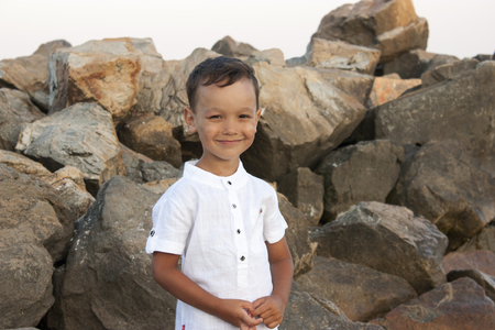 Boy child on sea stones smiles beautifullyの写真素材