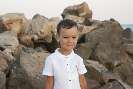 Boy child on sea stones smiles beautifullyの写真素材