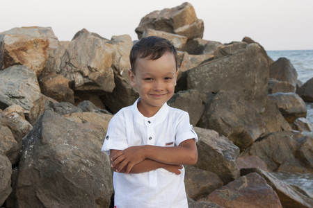 Boy child on sea stones smiles beautifully