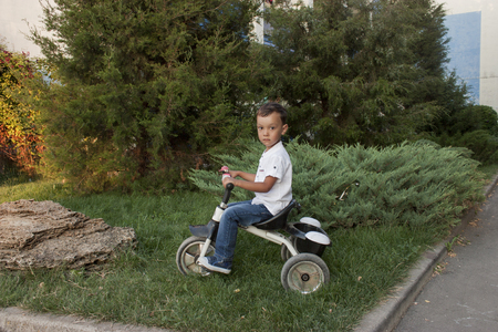 4 year old beautiful boy in a white shirt smiling on a bicycleの写真素材
