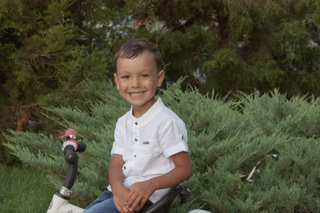 4 year old beautiful boy in a white shirt smiling on a bicycleの写真素材
