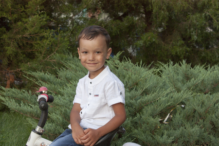 4 year old beautiful boy in a white shirt smiling on a bicycleの写真素材