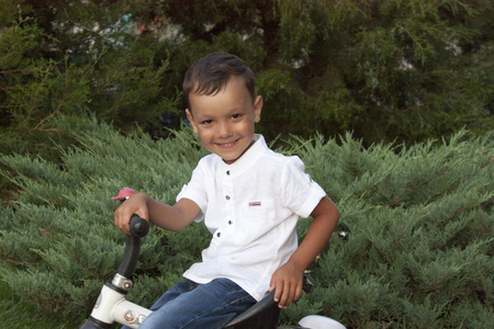 4 year old beautiful boy in a white shirt smiling on a bicycleの写真素材