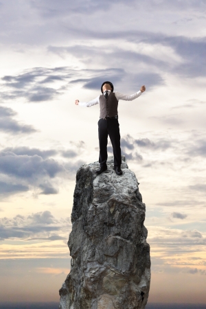 Happy businessman on the rock mountain.の写真素材