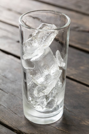 Glass of empty water with ice on the wooden tableの写真素材