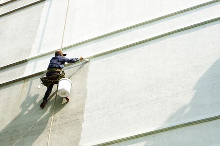 painter hanging on white buildingの写真素材