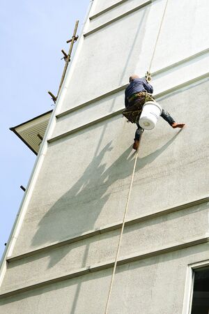 painter hanging on white buildingの写真素材