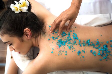 beautiful and healthy woman enjoying during a salt scrub back massage in spa salonの写真素材