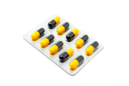 yellow and black capsule in blister pack isolated on white background.の写真素材