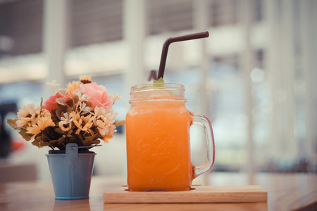 Orange juice with a vase of flowers in a restaurant.Style Vintageの写真素材