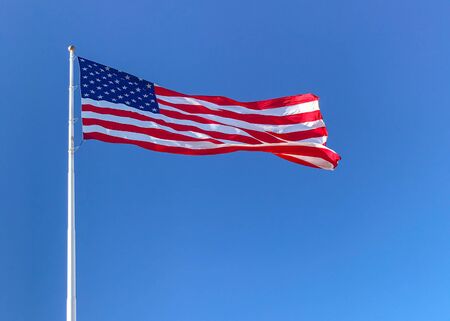 American flag waving in blue sky.の写真素材