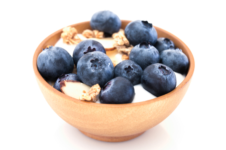 Yogurt with granola and organic blueberries in wooden bowl on white background.の写真素材