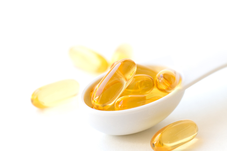 Fish oil capsules in a spoons on white background.の写真素材