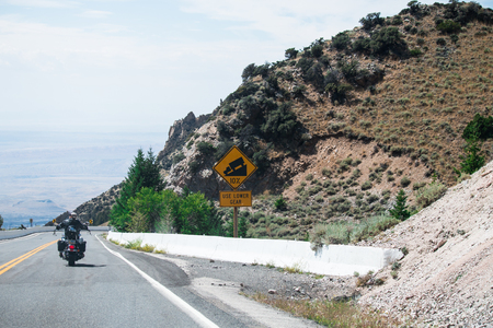 Sign of traffic alerts downhill slope 10 %, reduce speed and use a lower gear. Drive with caution.の写真素材