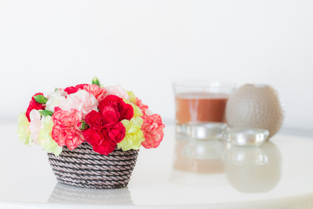 Colorful carnations in brown vase and candle on marble table.の写真素材