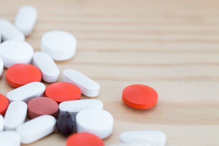 White, black and red medicine pills on a wooden background.の写真素材