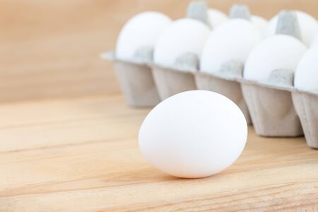 Close-up of raw chicken eggs in egg box on wooden backgroundの写真素材