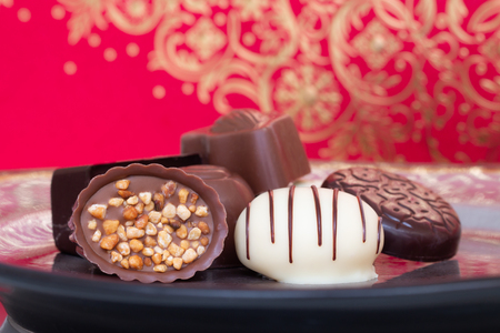 Assorted gourmet chocolate candies in different shapes and colors in the dish.の写真素材