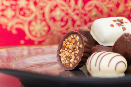 Assorted gourmet chocolate candies in different shapes and colors in the dish.の写真素材