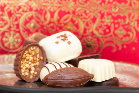 Assorted gourmet chocolate candies in different shapes and colors in the dish.の写真素材