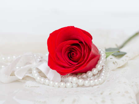 Close up of red rose on white lace and pearls dedorated around.の写真素材