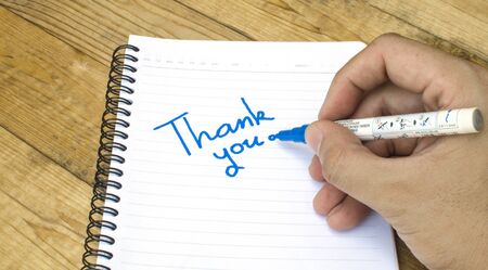 Thank you wording on a book by hand on wooden backgroundの写真素材