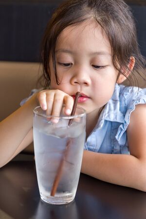 Child Using Straw to Drink Water from Glassの写真素材