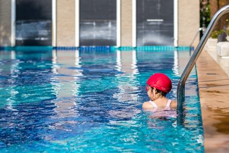 Child Resting at Edge of Swimming Pool After Swimming Trainingの写真素材