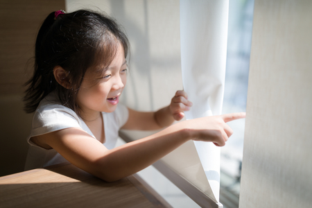 Exploring Concept Illustrated by Asian Child Looking and Pointing Out Windowの写真素材
