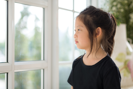 Lonely Asian Child Looking Out Windowの写真素材