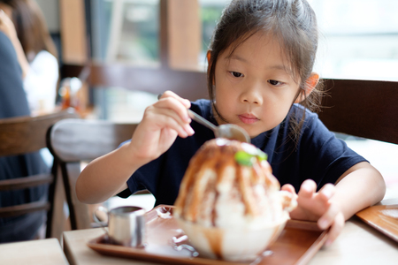 Happy Asian child enjoys eating Korean Patbingsu or Bingsu, shave ice frozen dessert.の写真素材