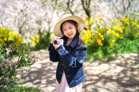 Asian child on her travelling trip for vacation holding camera to take photo.の写真素材