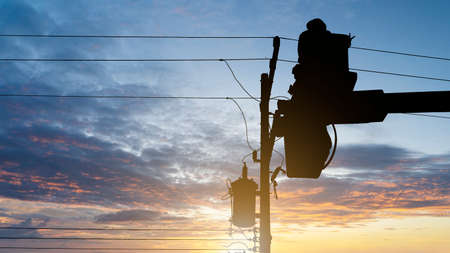 Silhouette maintenance of electricians work with high voltage electricity on the hydraulic bucket on...