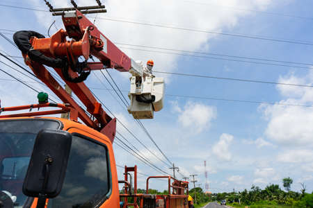 Electrician works on a basket. Technicians are repairing high voltage system.