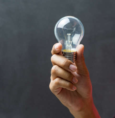 Light bulb and hand concept on black background